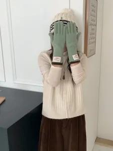 Guanti in maglia verde salvia con etichetta Bonjour e bordo marrone su una modella