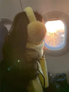 Detail of yellow plush earmuffs and matching scarf with black wavy stitched edges