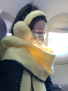 Detail of yellow wool scarf with black stitched edges and matching plush ear muffs