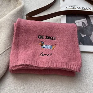 Detail of pink knitted scarf featuring a cute embroidered dachshund dog and heart pattern