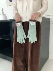 Texture a maglia dettagliata dei guanti termici verde menta con polsini marrone scuro