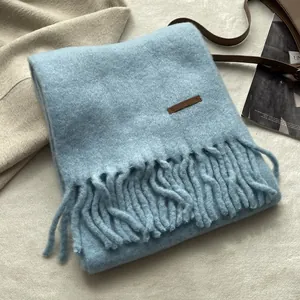 Detail of light blue thick scarf featuring soft brushed texture and fringe tassels