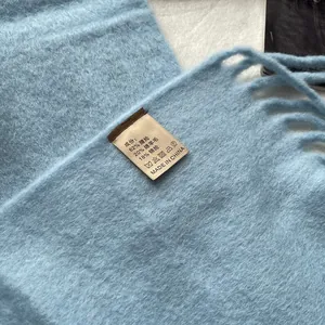 Detail of light blue wool blend scarf texture showing fuzzy fabric and product label