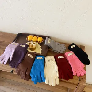 Detailed close-up of knitted winter gloves showing ribbed cuffs and brand logo labels