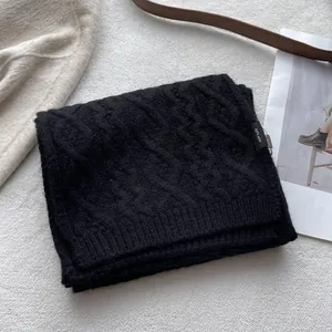 Detail of 100% merino wool scarf featuring thick cable knit texture and ribbed edges