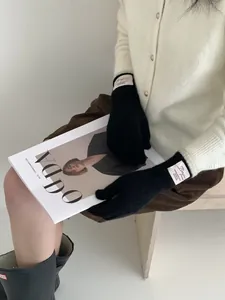 Dettaglio di guanti neri in maglia con etichetta Bonjour e outfit casual elegante