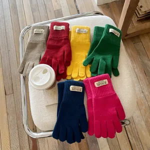 Winter knitted touchscreen gloves in six colors displayed on a cozy folding chair