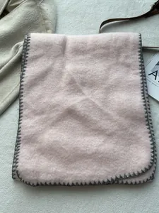 Close-up of pink wool scarf with grey blanket stitch edge detailing and soft texture