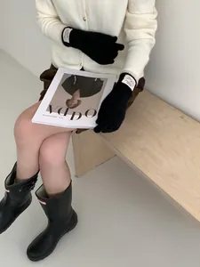 Dettaglio guanti in maglia neri con etichetta Bonjour su un outfit alla moda