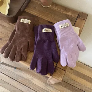 Detail of brown and purple thick knitted touchscreen gloves on a wooden tray