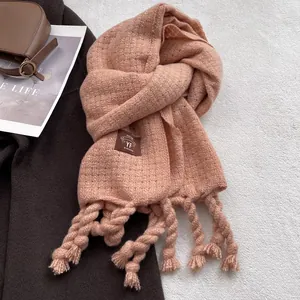 Detalle de bufanda rosa-naranja gruesa tacto cachemira con borlas y etiqueta de cuero