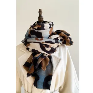 Thick leopard print cashmere shawl scarf with tassels worn over a white wool coat