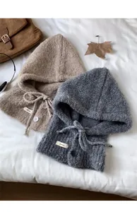 Flat lay of knit balaclavas in beige and grey with drawstring and button details