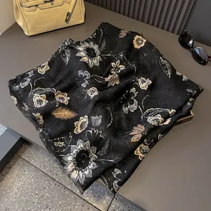 Detail of black and gold floral scarf with soft fringe edges and premium silk texture