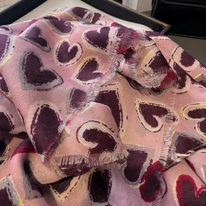 Detail of pink cotton linen scarf with heart prints and subtle gold metallic threading