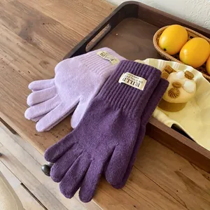 Detail of warm knitted gloves in light and dark purple with ribbed cuffs and trendy labels