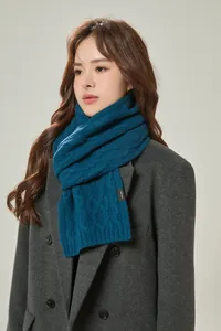 Detailed close-up of dark blue cable knit texture and 100% merino wool quality label