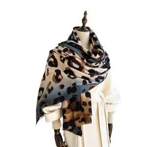 Leopard print scarf with blue gradient and fringe on a beige coat display