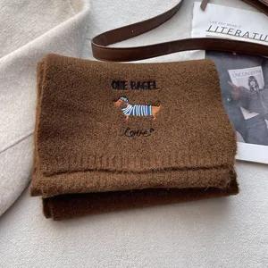 Close-up of brown knit scarf with detailed dachshund embroidery and heart pattern