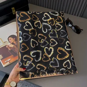 Close-up of black cotton-linen scarf featuring gold heart prints and fringe details