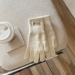 Detailed shot of knitted warm gloves showing ribbed cuffs and branded fabric label