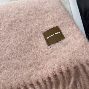 Soft pink wool blend scarf with tassel edges and premium leather label detail
