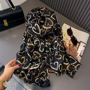 Detail of premium black linen scarf with gold heart print and raw fringe edges