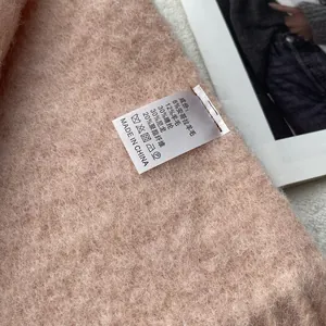 Close-up of soft pink wool blend fabric texture with detailed white care label
