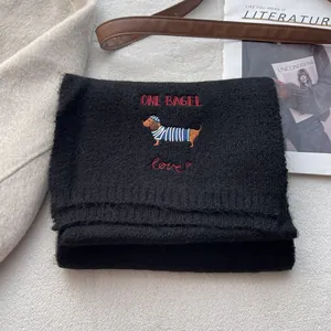 Detail of dachshund embroidery with One Bagel text on a premium black knitted scarf