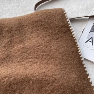 Brown fleece shoulder bag with white whipstitch edges and thin leather strap for autumn