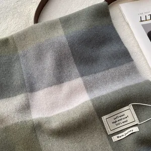 Gros plan détaillé d'une écharpe 100% laine avec texture à carreaux pastel et franges