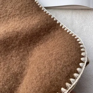 Thick brown wool scarf with white blanket stitched edges in a minimalist aesthetic