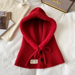 Detail of red knit balaclava hat with white faux shearling trim and drawstring bow