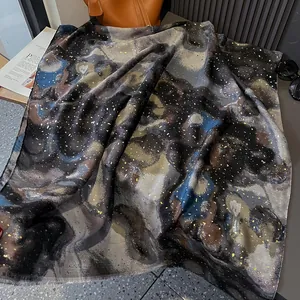 Artistic gold foil scarf with abstract landscape print and fringed edges on table