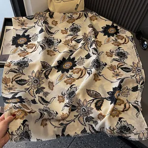 Detail of floral print scarf with refined fringed edges on an elegant beige fabric