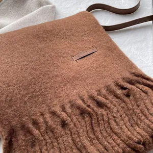 Close-up of deep brown wool scarf with dense fringe detail and brown leather strap