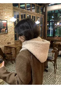 Detailed close-up of fluffy beige knit balaclava hood worn with a brown woolen coat