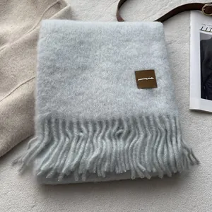 Close-up of soft wool blend scarf with fringe detail and minimalist leather label