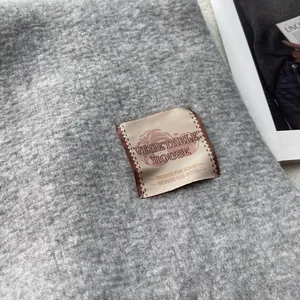 Close-up of thick grey faux cashmere scarf fabric with premium woven brand label