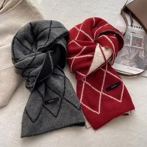 Thick wool knit scarves with argyle patterns in grey and red on a soft rug