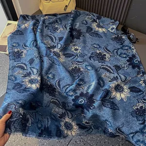 Close-up of blue floral scarf with elegant fringe detail and silk-like textured finish