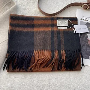 Detail of 100% Australian wool scarf featuring a classic plaid pattern and fringe edges