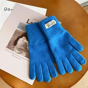 Close-up of Klein blue knitted gloves featuring ribbed cuffs and branded fabric label