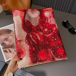 Close-up of artistic red and pink scarf with gold foil details and soft fringe finish