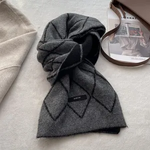 Detail shot of the thick grey and black diamond lattice knit wool scarf with brand label
