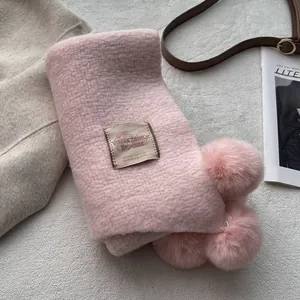 Detail of pink faux cashmere scarf with fluffy pompom accents and retro textile label