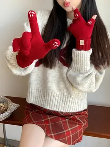 Close-up of red knit mittens with white cat paw embroidery and functional flap cover
