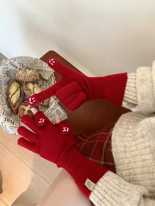Detail of red knit gloves with white cartoon embroidery and ribbed cuffs on female model