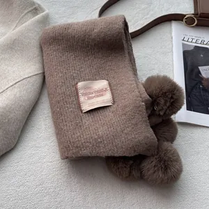 Detail of brown faux cashmere scarf with fluffy pom-poms and vintage brand label