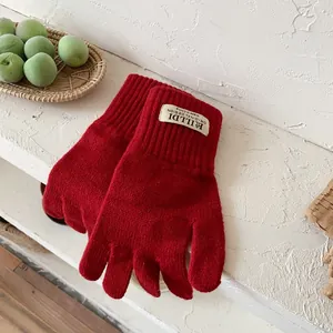 Detailed texture of red knitted gloves with ribbed cuffs and decorative brand label